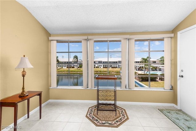 interior details with baseboards, a water view, and a textured ceiling