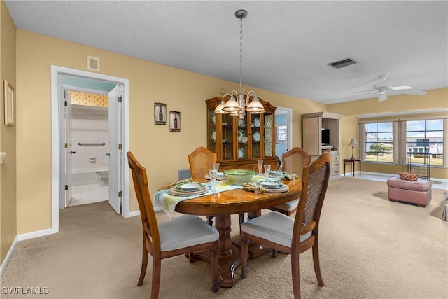 dining space featuring visible vents, baseboards, ceiling fan with notable chandelier, and light carpet