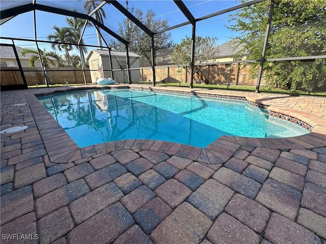 view of pool featuring a patio, glass enclosure, and a shed