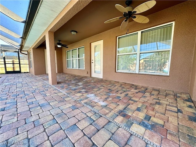 view of patio featuring ceiling fan and glass enclosure