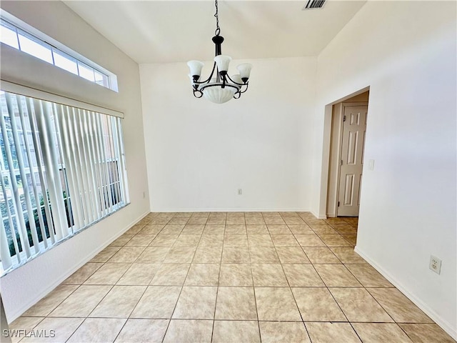 tiled empty room featuring an inviting chandelier