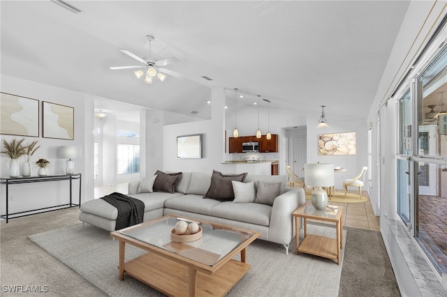 carpeted living room with ceiling fan and vaulted ceiling