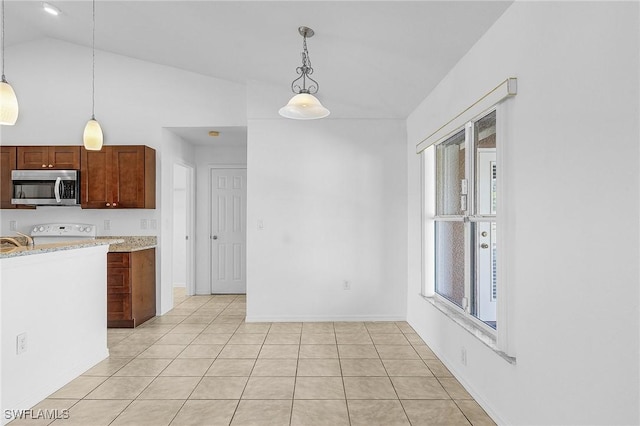 kitchen featuring lofted ceiling, sink, decorative light fixtures, light tile patterned floors, and stove