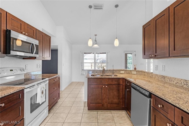 kitchen featuring vaulted ceiling, appliances with stainless steel finishes, decorative light fixtures, sink, and light stone countertops