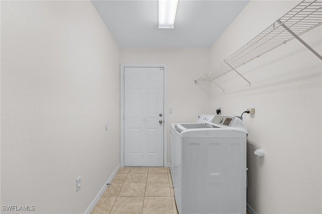 clothes washing area featuring washer and clothes dryer and light tile patterned floors