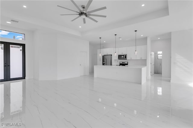 unfurnished living room with french doors, a tray ceiling, and ceiling fan