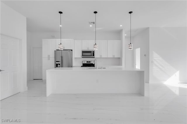 kitchen featuring hanging light fixtures, white cabinetry, a kitchen island with sink, sink, and stainless steel appliances