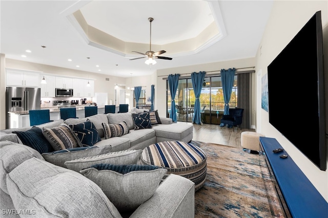 living room featuring wood-type flooring, a raised ceiling, and ceiling fan