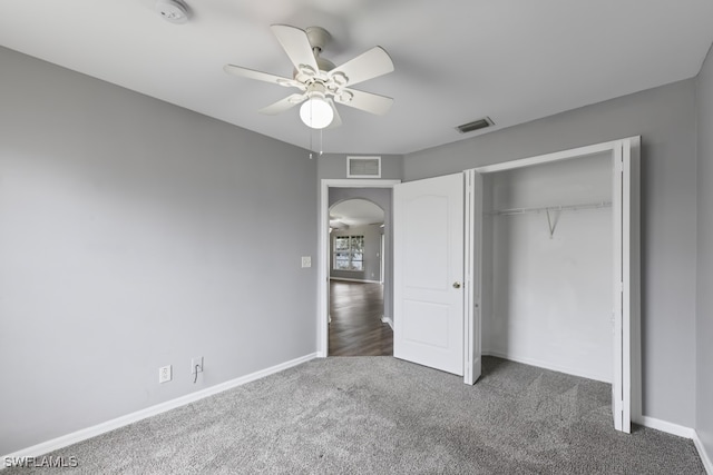 unfurnished bedroom featuring a closet, dark carpet, and ceiling fan