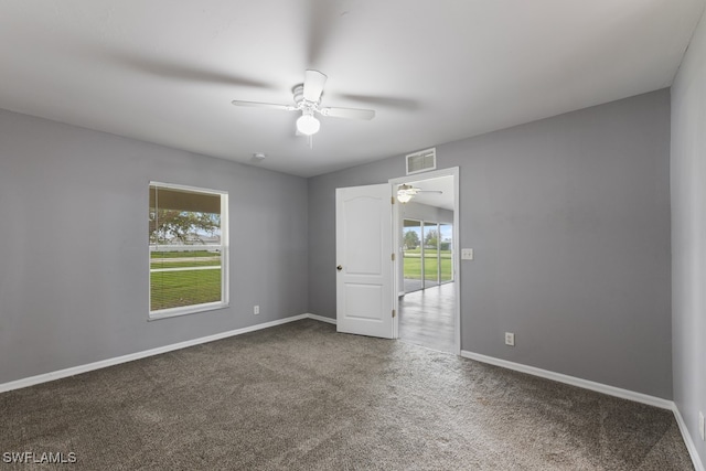 carpeted empty room with ceiling fan and a wealth of natural light