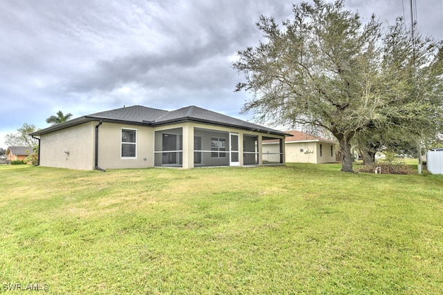 rear view of house with a lawn and a sunroom