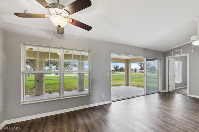 empty room with dark hardwood / wood-style flooring, ceiling fan, vaulted ceiling, and a wealth of natural light