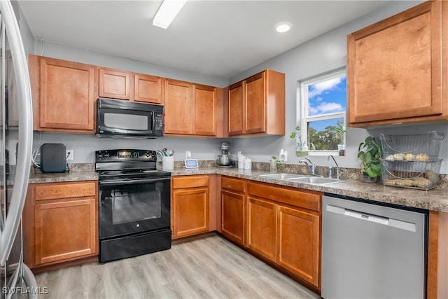 kitchen with light wood-type flooring, black appliances, and sink