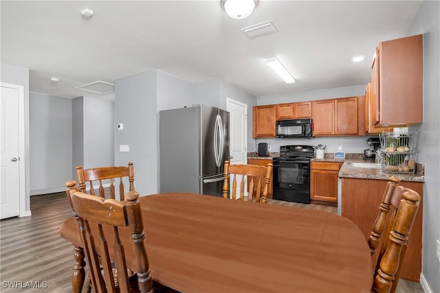 kitchen featuring light hardwood / wood-style floors, black appliances, sink, and light stone counters