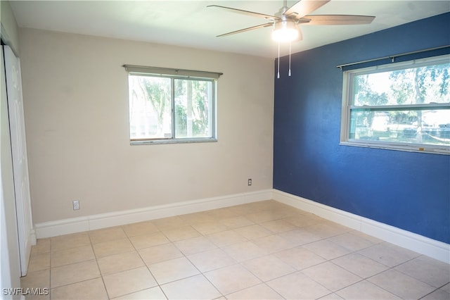 empty room featuring ceiling fan, light tile patterned floors, and plenty of natural light