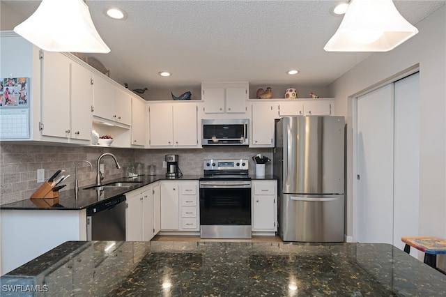 kitchen with decorative backsplash, stainless steel appliances, sink, white cabinetry, and a textured ceiling