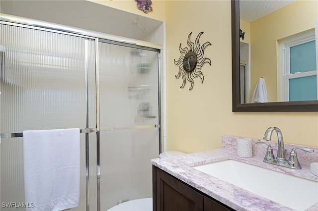 bathroom featuring vanity, a shower with shower door, a textured ceiling, and toilet