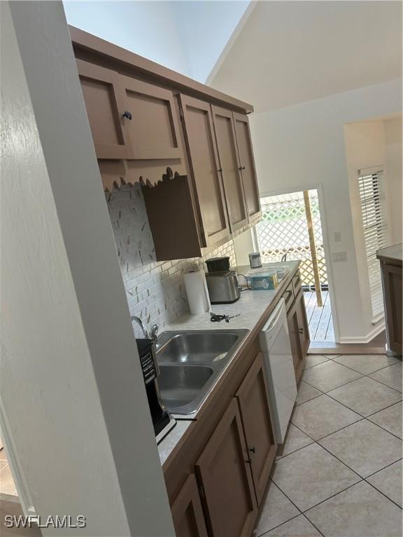 kitchen featuring tasteful backsplash, dishwasher, light tile patterned floors, and sink