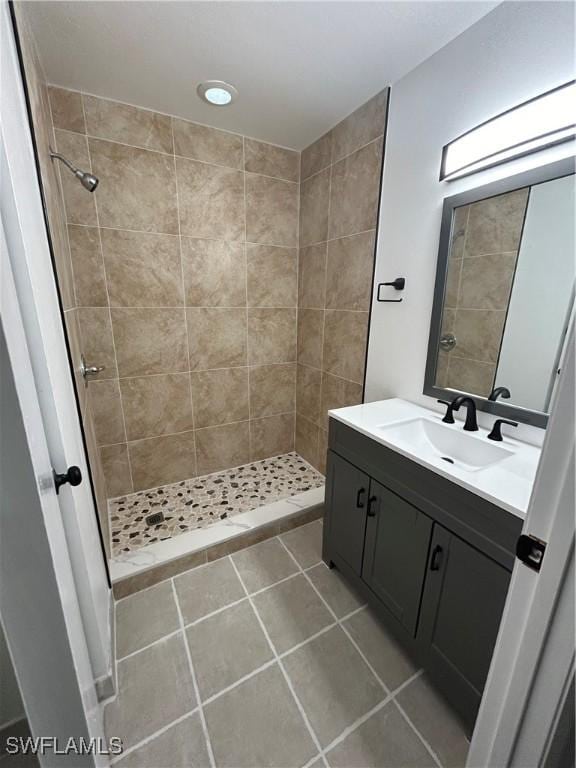 bathroom with tile patterned flooring, vanity, and tiled shower