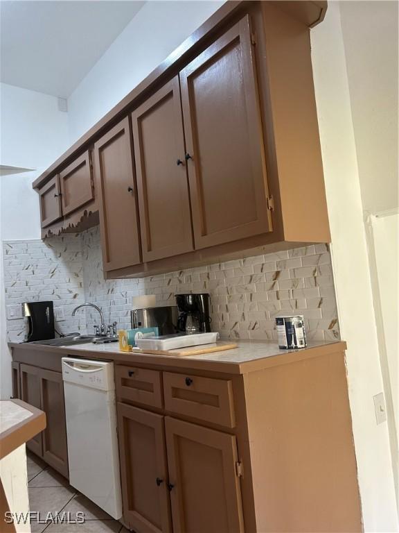 kitchen with light tile patterned flooring, white dishwasher, tasteful backsplash, and sink