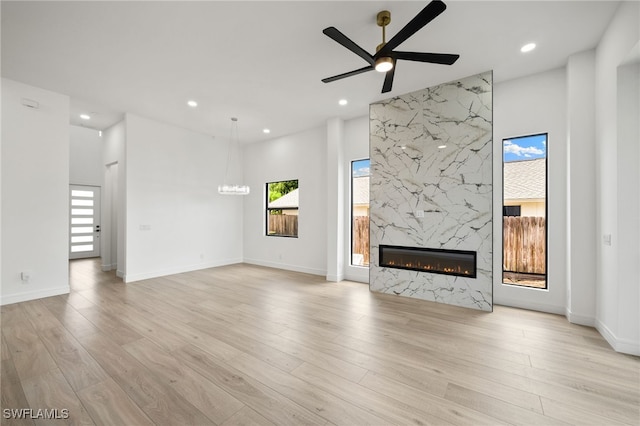 unfurnished living room featuring a fireplace, light hardwood / wood-style floors, and ceiling fan