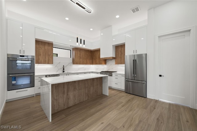 kitchen featuring appliances with stainless steel finishes, light hardwood / wood-style flooring, and white cabinetry