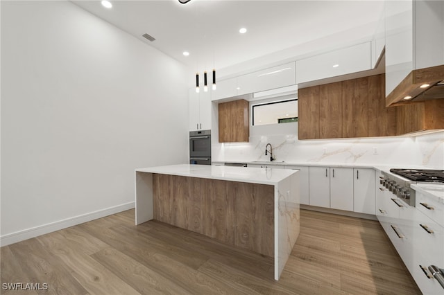 kitchen featuring appliances with stainless steel finishes, premium range hood, a center island, light hardwood / wood-style floors, and white cabinetry