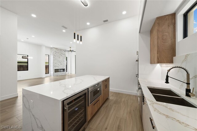 kitchen featuring wine cooler, sink, a center island, and light hardwood / wood-style flooring