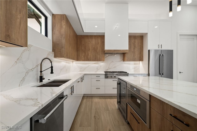 kitchen with sink, white cabinets, light wood-type flooring, and appliances with stainless steel finishes