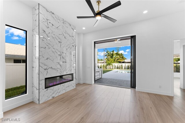 unfurnished living room featuring a fireplace, light hardwood / wood-style flooring, and a healthy amount of sunlight