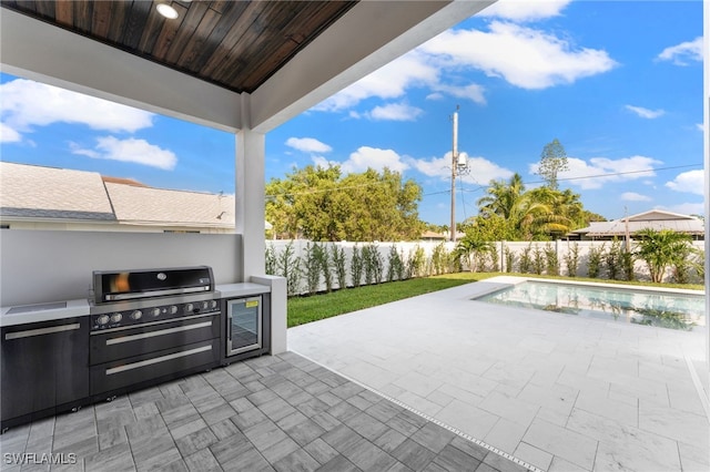 view of patio / terrace with wine cooler, a fenced in pool, and area for grilling