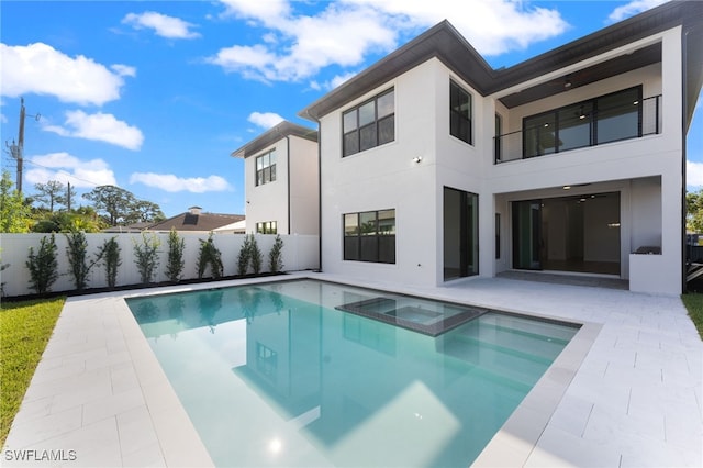 rear view of property featuring a balcony, a patio, and a pool with hot tub