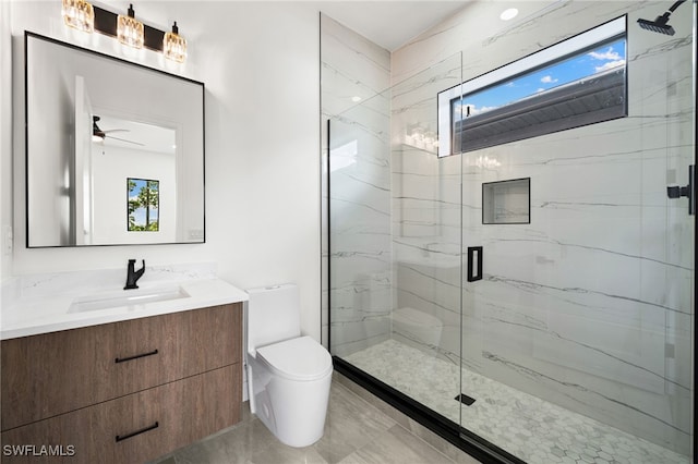 bathroom featuring ceiling fan, vanity, a shower with shower door, and toilet