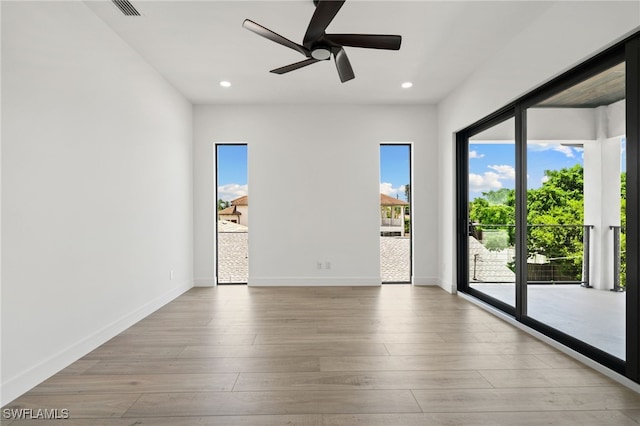 spare room featuring ceiling fan, a healthy amount of sunlight, and light wood-type flooring