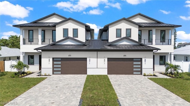 view of front of house featuring a front yard, a balcony, and a garage