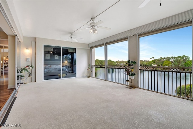 unfurnished sunroom with a water view and ceiling fan