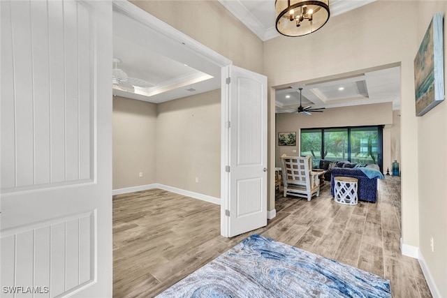 foyer with coffered ceiling, ceiling fan with notable chandelier, crown molding, light hardwood / wood-style flooring, and beamed ceiling