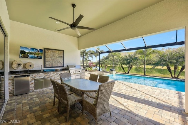 view of patio featuring ceiling fan, glass enclosure, an outdoor kitchen, a grill, and an outdoor pool