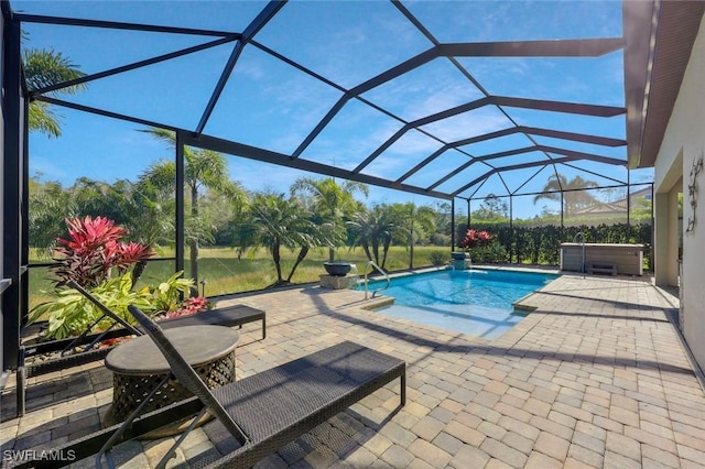 outdoor pool with a patio, glass enclosure, and a hot tub