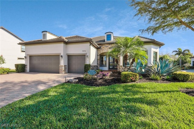 mediterranean / spanish-style house with decorative driveway, stone siding, a front lawn, and an attached garage