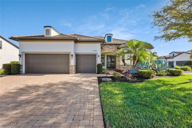 view of front facade with a garage, stone siding, decorative driveway, and stucco siding