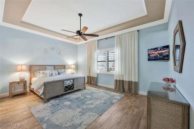 bedroom featuring a raised ceiling, baseboards, and wood finished floors