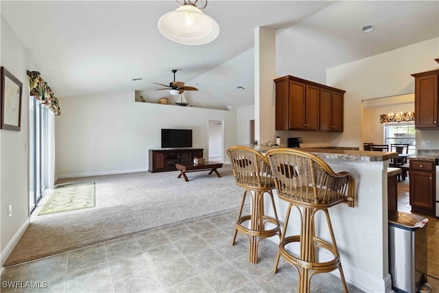 kitchen featuring kitchen peninsula, ceiling fan, light carpet, high vaulted ceiling, and a breakfast bar