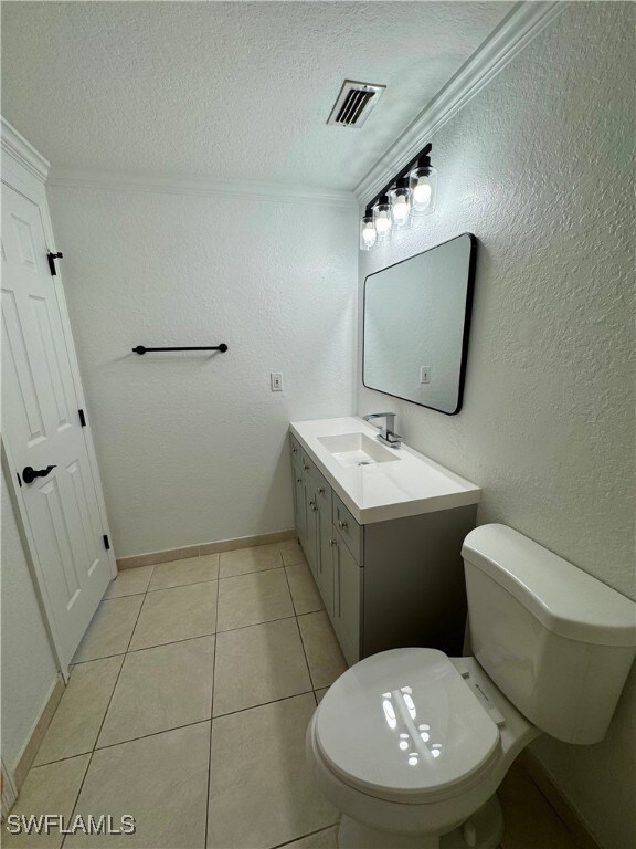 bathroom featuring vanity, crown molding, toilet, and tile patterned flooring