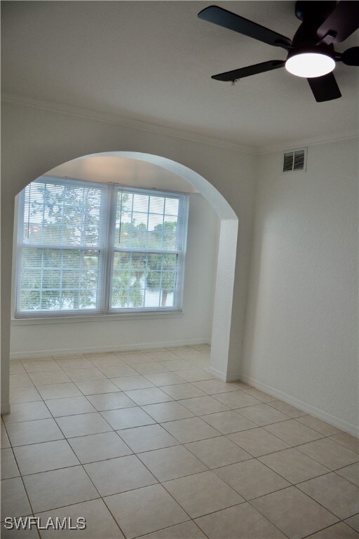 spare room with ornamental molding, ceiling fan, and light tile patterned floors