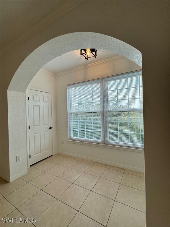 tiled spare room with ornamental molding