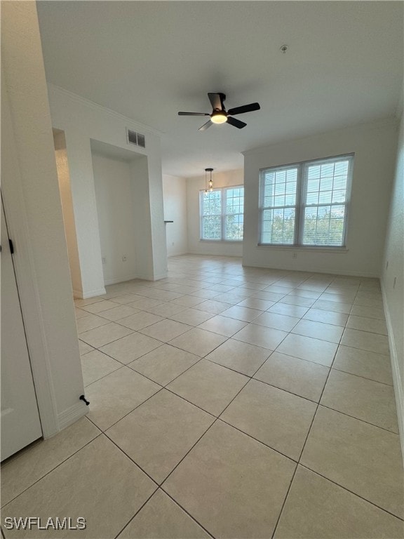 empty room with ceiling fan, crown molding, and light tile patterned floors