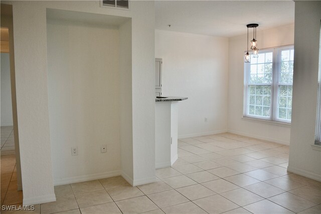 unfurnished dining area featuring ornamental molding and light tile patterned floors