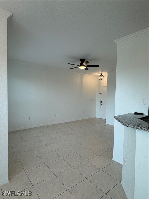 tiled spare room with ornamental molding and ceiling fan