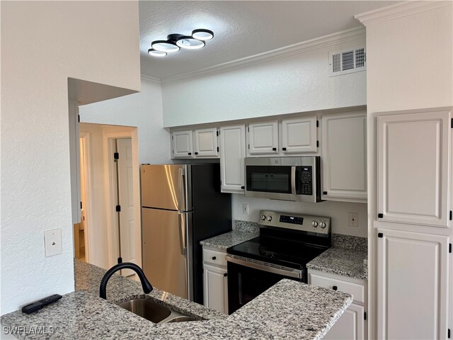 kitchen with kitchen peninsula, sink, crown molding, appliances with stainless steel finishes, and light stone counters